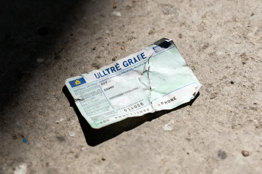 Papier froissé "ULTRÉ GRAIE" sur sol en béton, éclairé par lumière naturelle.