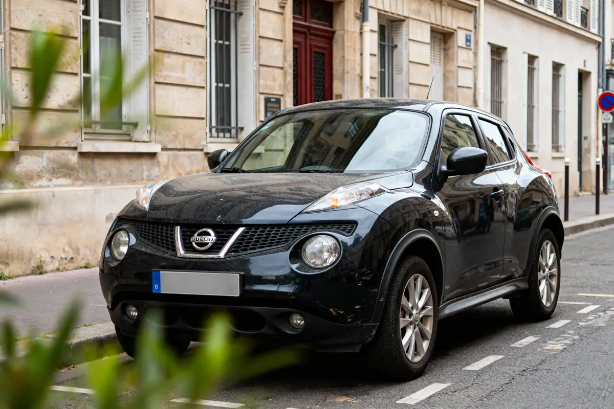 Voiture noire stationnée dans une rue urbaine avec immeubles en arrière-plan.