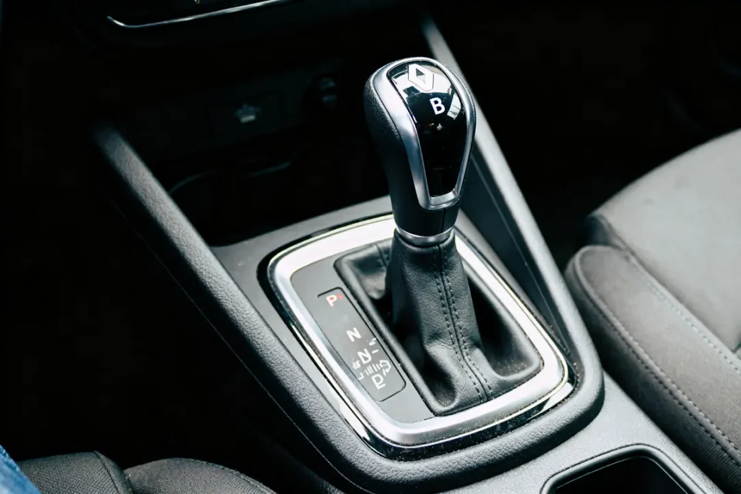 Levier de vitesse automatique d'une voiture, avec détails de positionnement, en intérieur sombre.