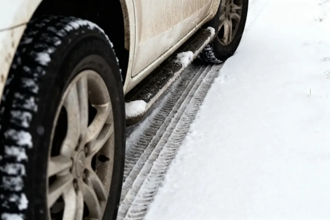Pneus de voiture, traces sur route enneigée, voiture blanche. Neige et boue visibles sur le véhicule.