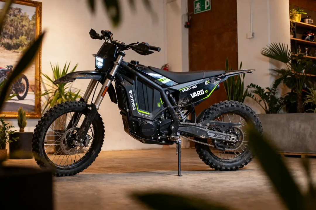 Moto électrique noire dans pièce avec plantes, éclairage naturel.
