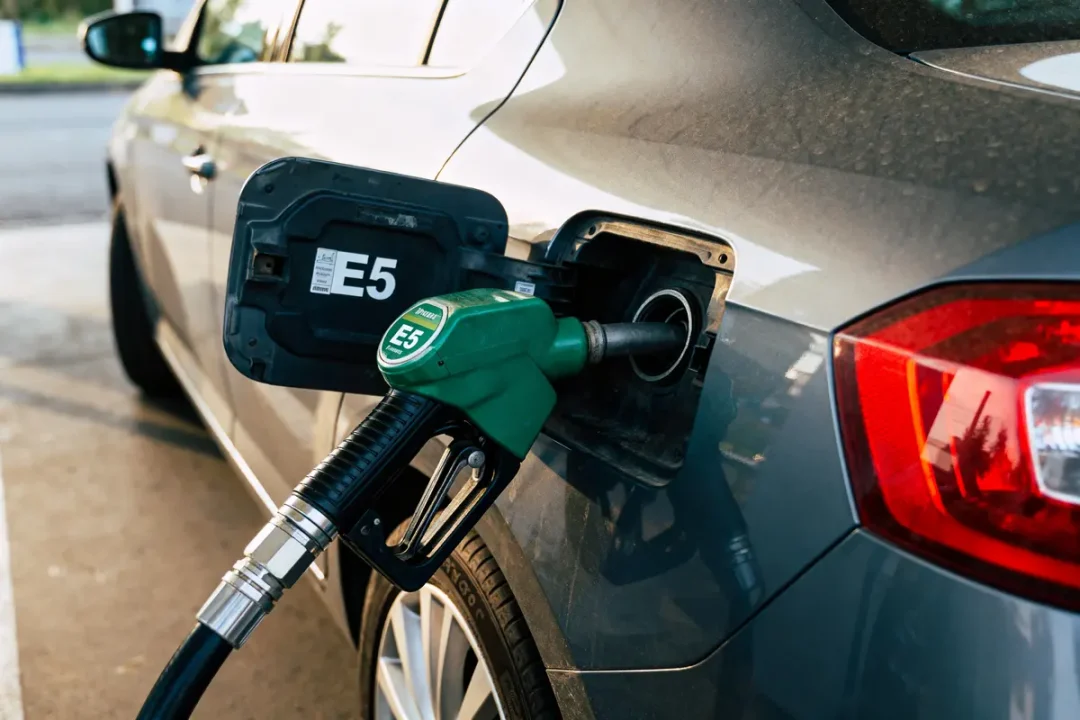 Voiture se faisant ravitailler en carburant E5 avec pompe verte dans une station-service.