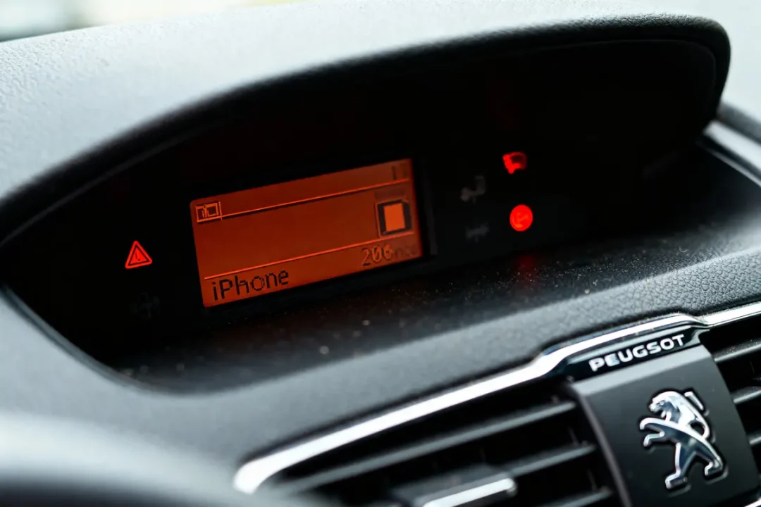 Tableau de bord Peugeot avec écran affichant "iPhone" et icônes de signalisation allumées.
