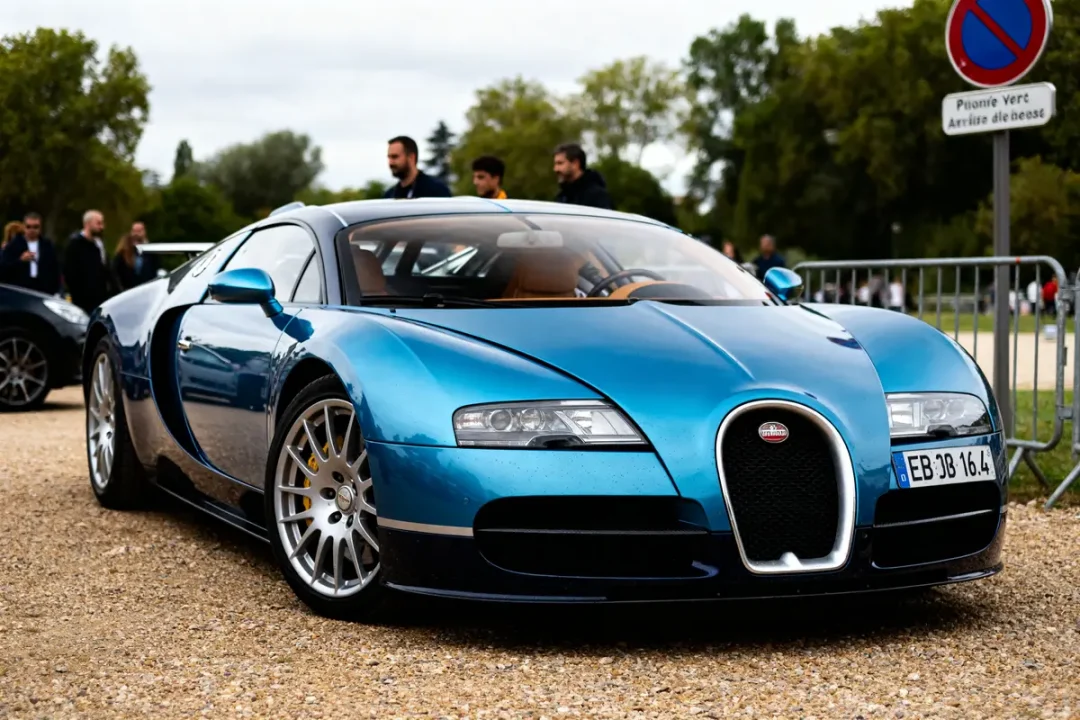 Voiture de luxe bleue EB 16.4 Veyron garée sur gravier avec passants en arrière-plan