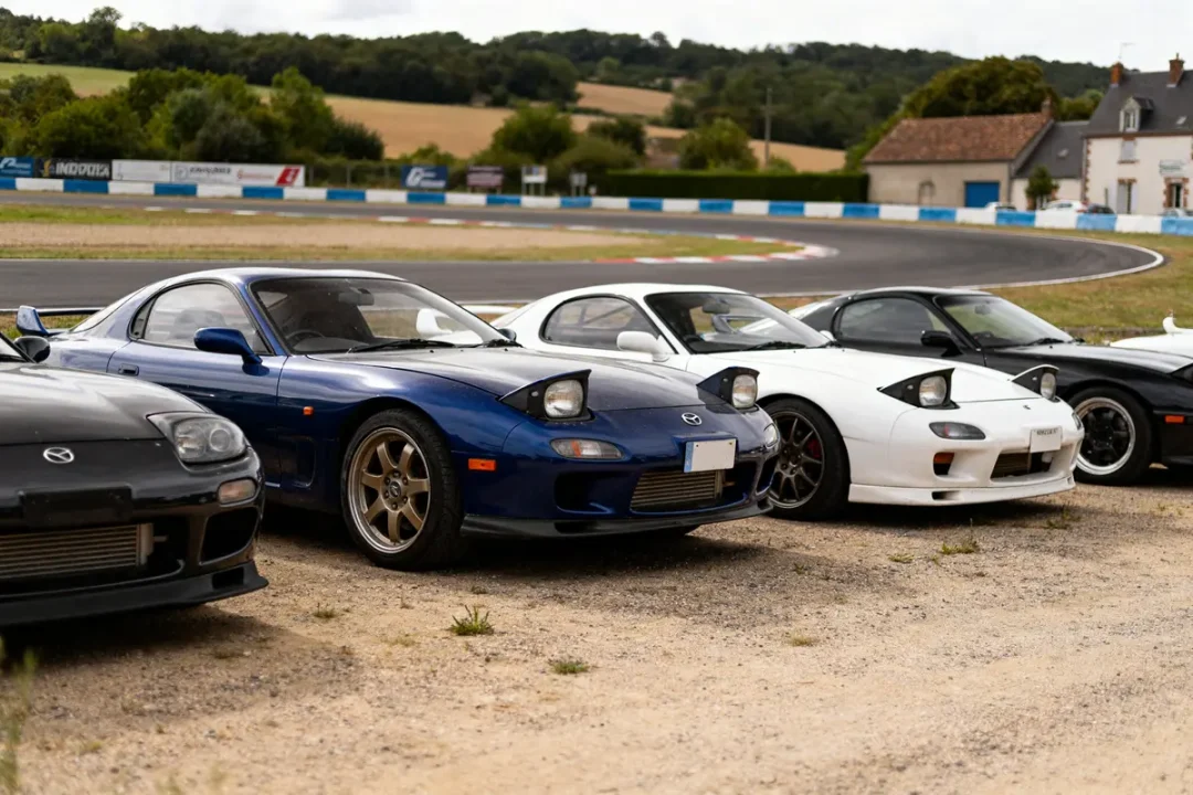 Mazda RX7 coupé bleu et blanc alignés sur circuit avec d'autres voitures sportives