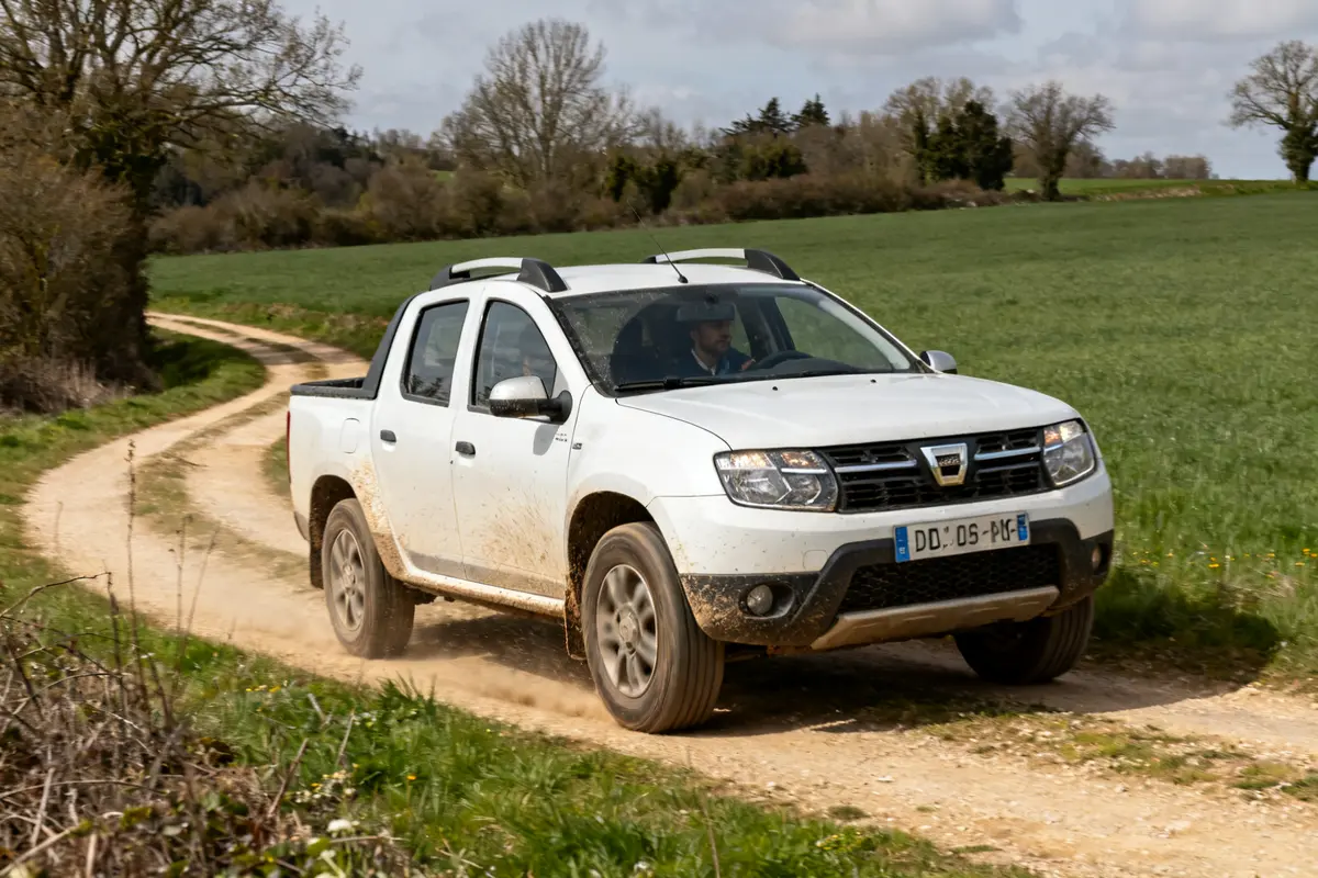 4x4 Dacia blanc roulant sur chemin de terre à travers la campagne verte
