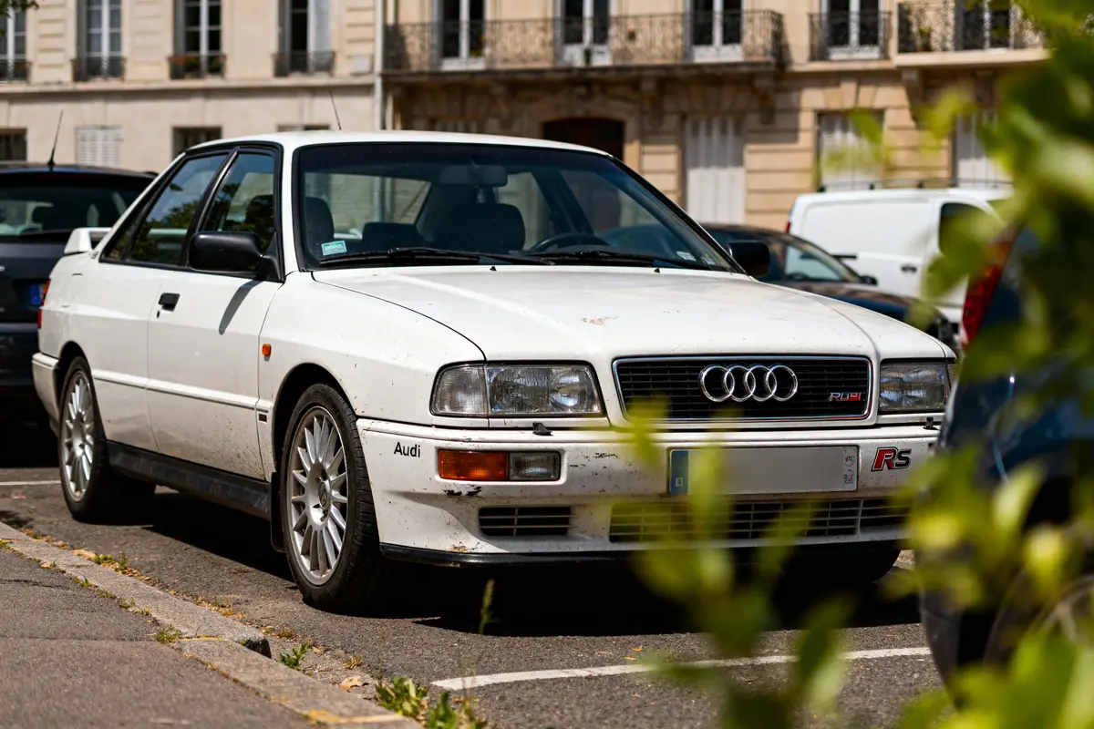 Audi RS2 Avant blanche garée sur une rue résidentielle avec façades en arrière-plan