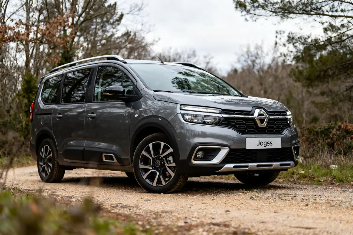 Véhicule gris Dacia Jogger stationné sur un chemin de terre en forêt