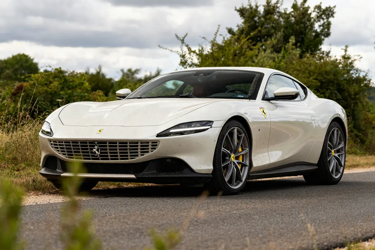 Ferrari Roma blanche stationnée sur une route de campagne entourée de verdure