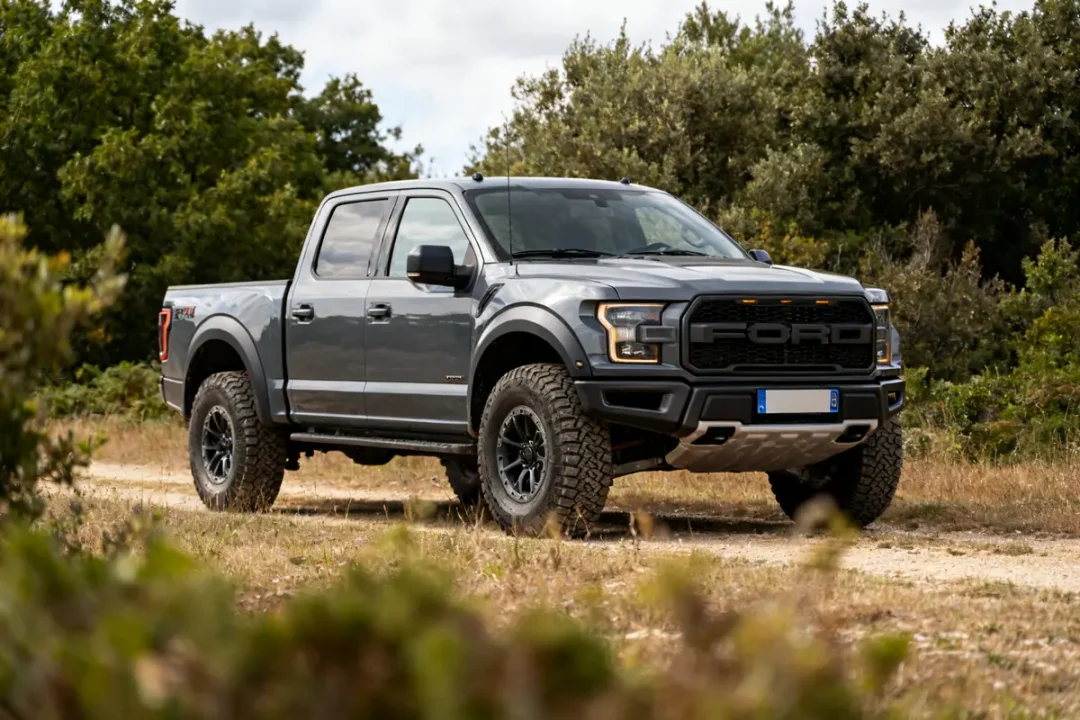 Pick-up Ford Raptor 4 door gris sur chemin forestier en pleine nature