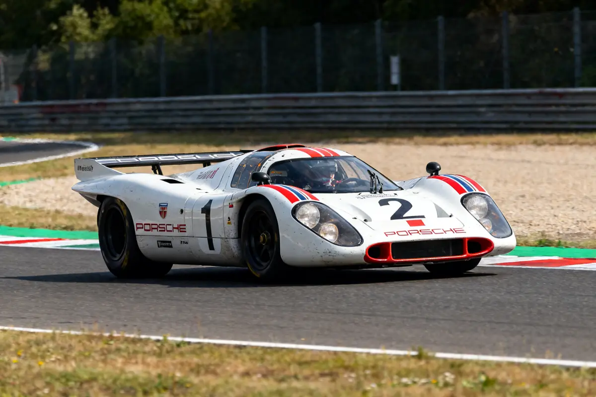 Course de la voiture légendaire Porsche 917 sur circuit avec des rayures rouges et bleues