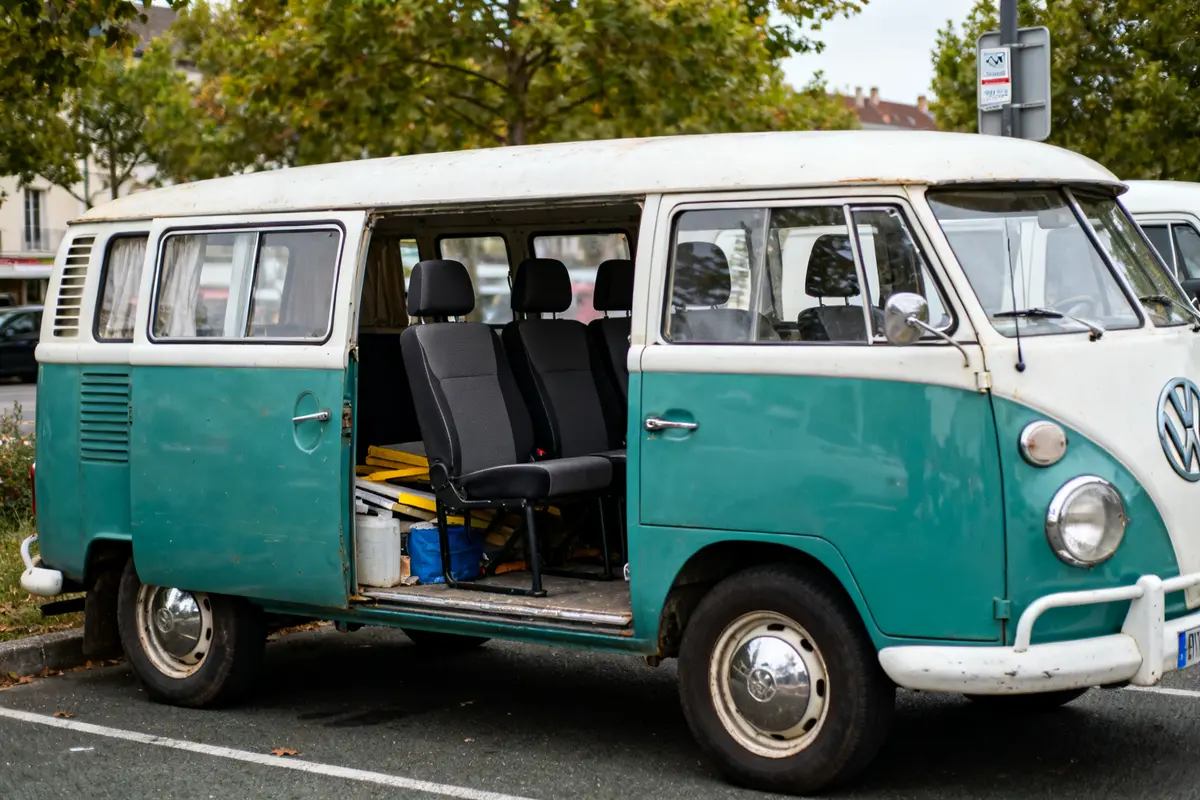 Un Volkswagen van vintage bleu avec porte latérale ouverte et sièges visibles.
