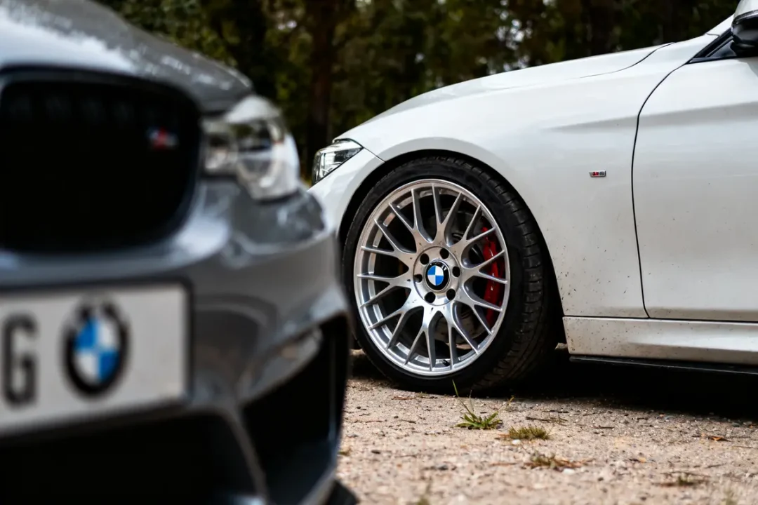Deux voitures BMW en extérieur, focus sur jantes para BMW sur fond arboré.