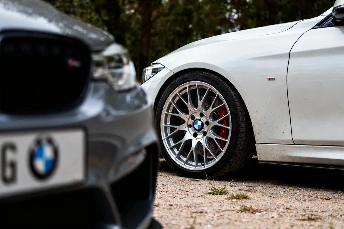 Deux voitures BMW en extérieur, focus sur jantes para BMW sur fond arboré.