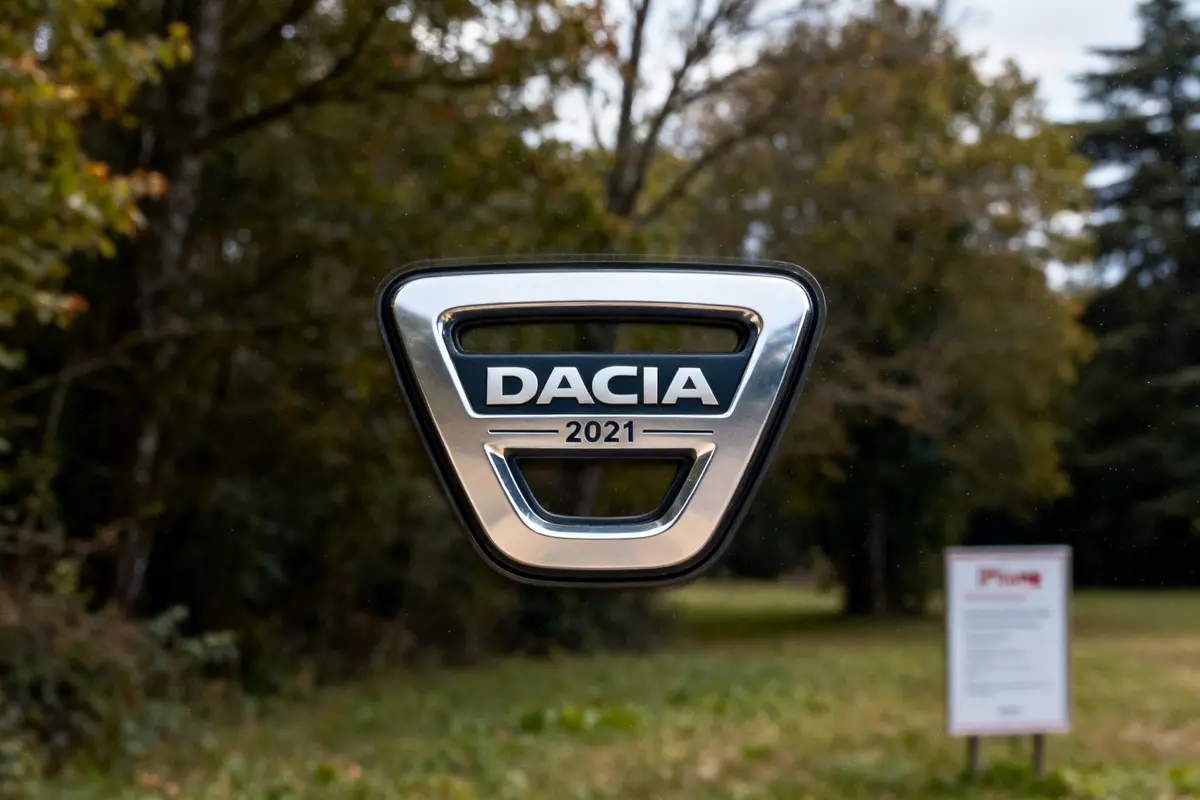 Logo Dacia 2021 en relief sur fond de paysage boisé flou