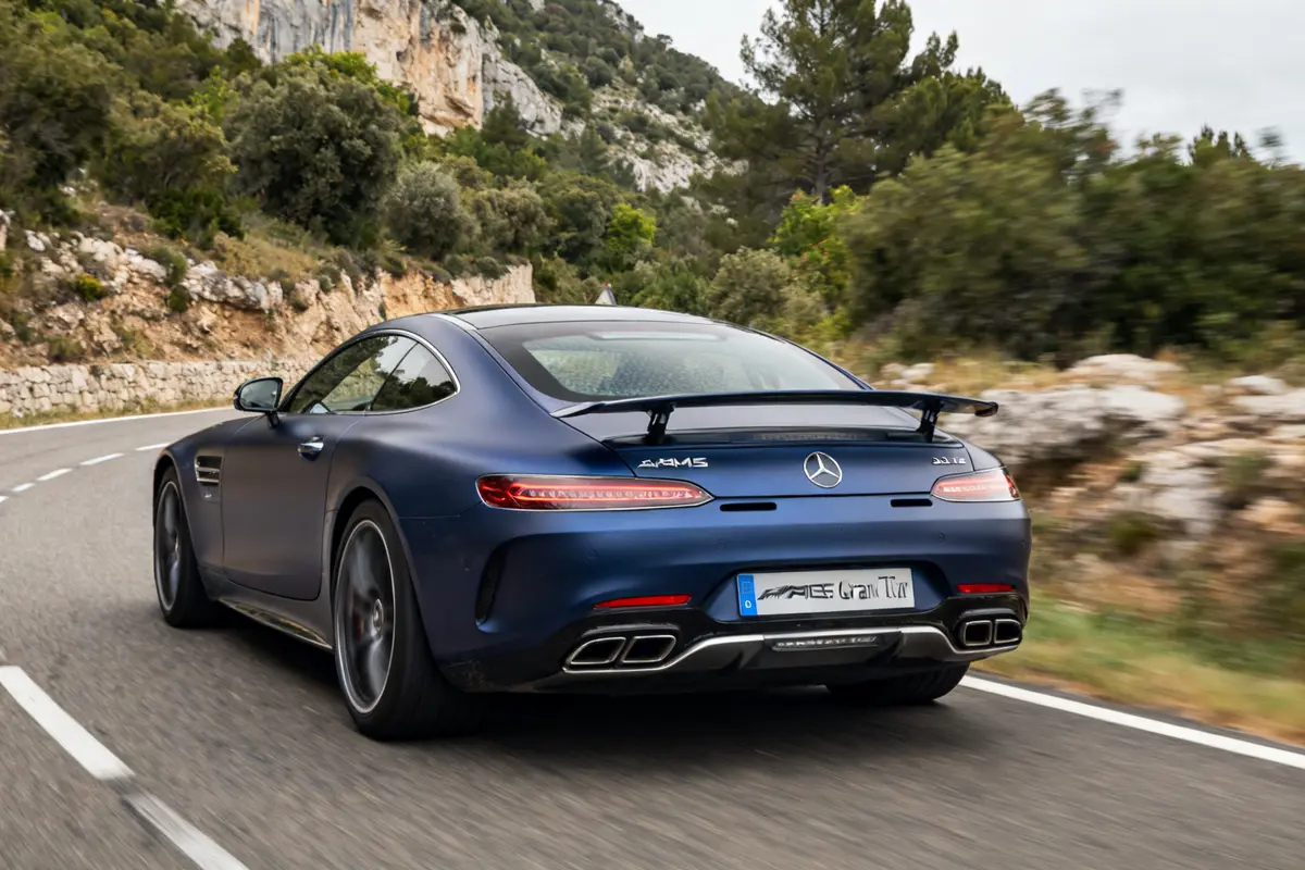 Voiture de sport Mercedes-AMG Gran Turismo bleue roulant sur une route sinueuse en montagne