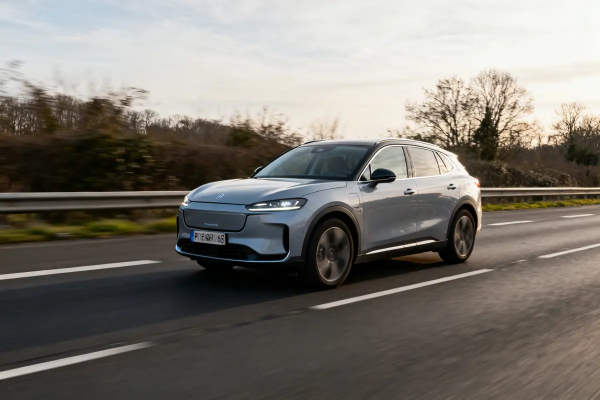 Voiture automatique grise roule sur autoroute en pleine nature au crépuscule
