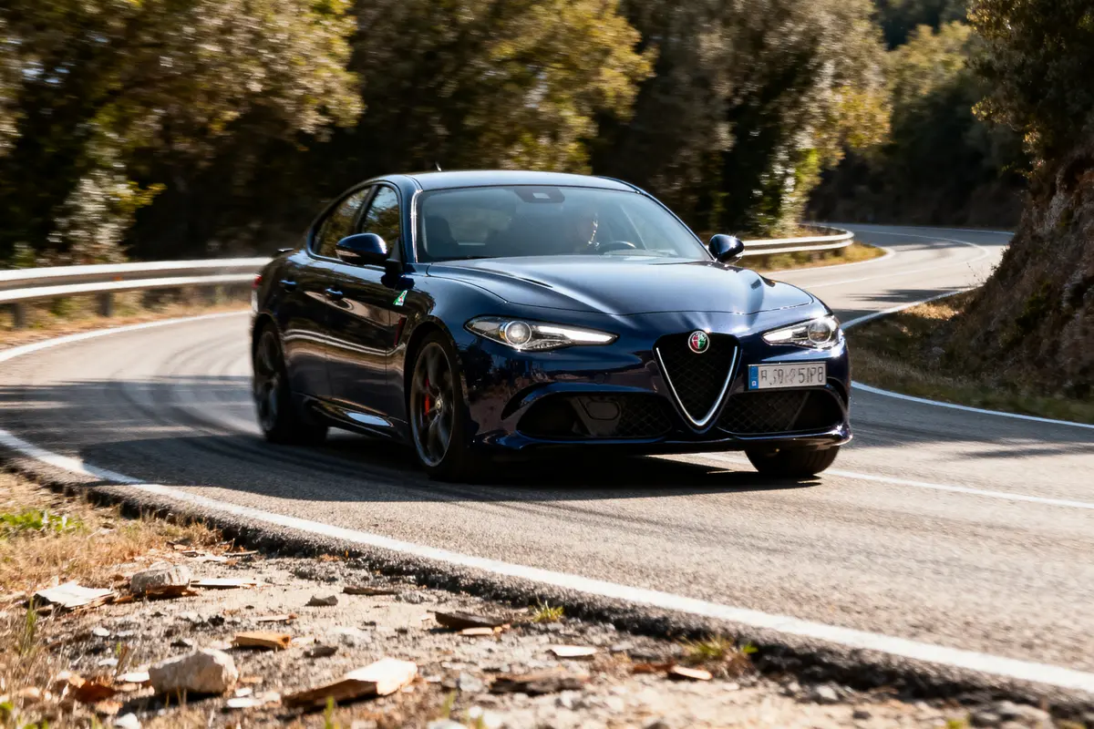 Voiture noire Alfa Romeo roulant sur route sinueuse bordée d'arbres, en journée.