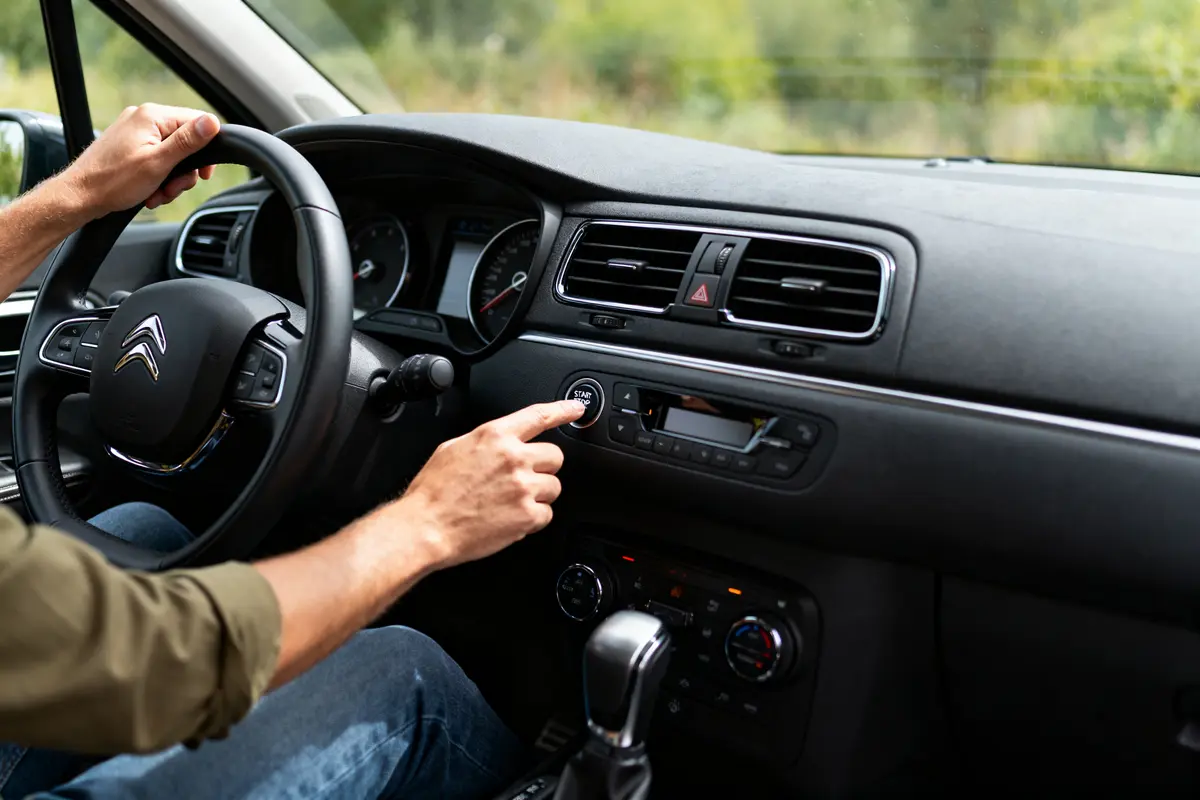 Conducteur dans une voiture Citroën, appuyant sur le bouton de démarrage du tableau de bord.