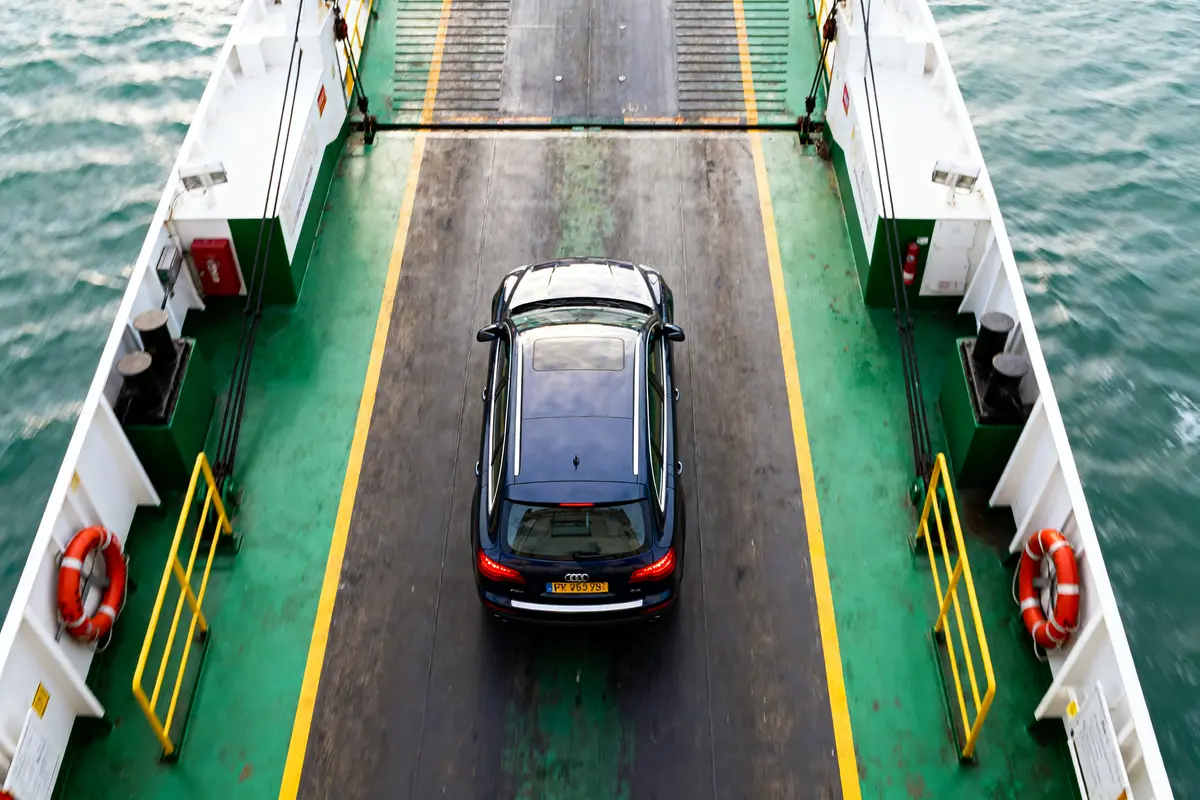 Voiture noire sur un ferry en mer, entourée de bordures vertes et blanches.